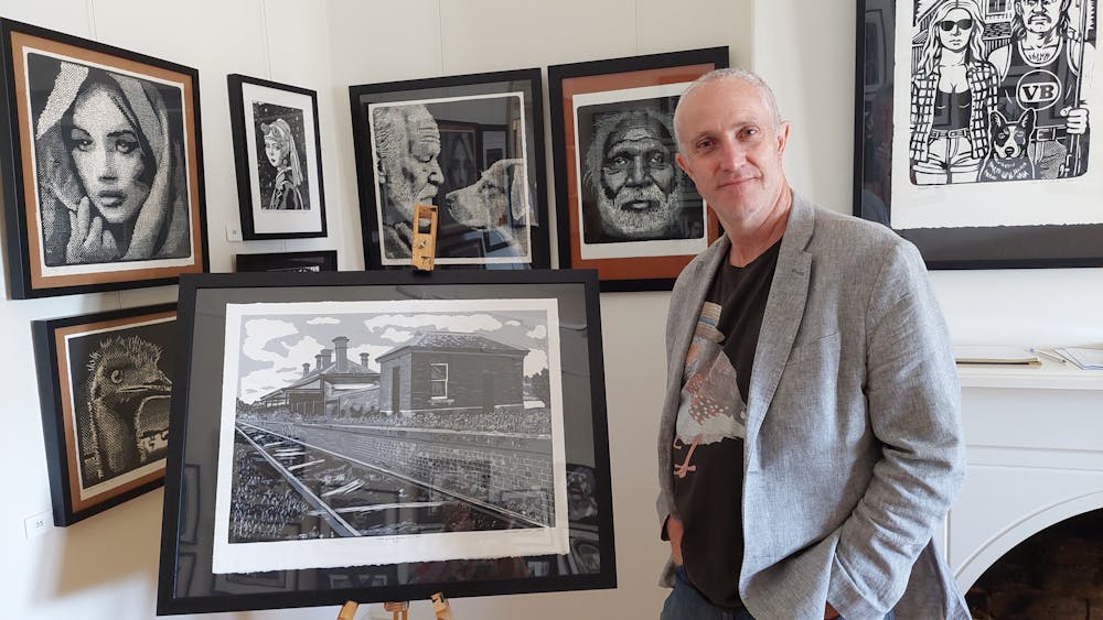 Colin is seen with his Black & White print of the Avoca Railway Station , plus other works