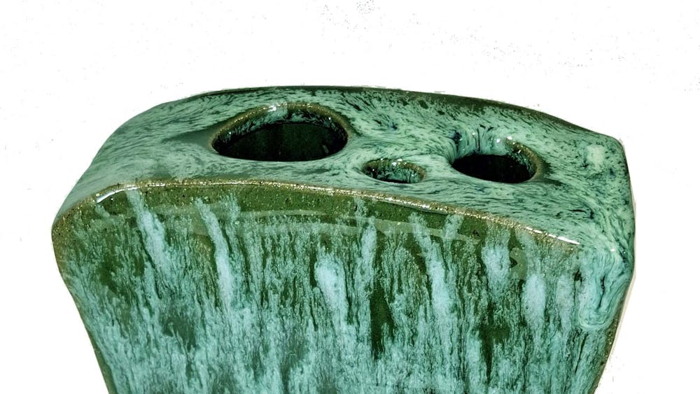 Angular ceramic vase with various shades of green glazing and 3 holes for flowers.