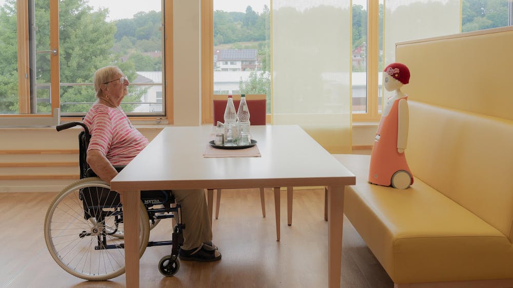 Waltraud talks with Emma, a social robot that recognises faces and remembers past conversations.