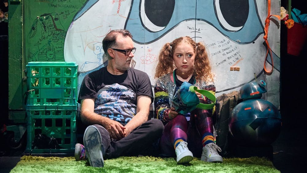 A father and his daughter sitting against a dumper talking