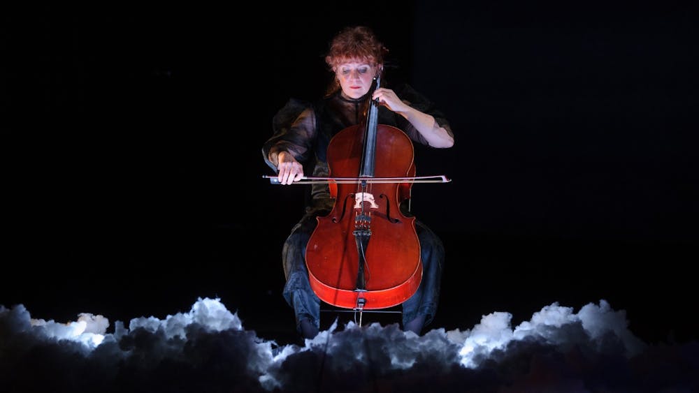 Zoë Barry playing the cello on an interactive cloud on stage