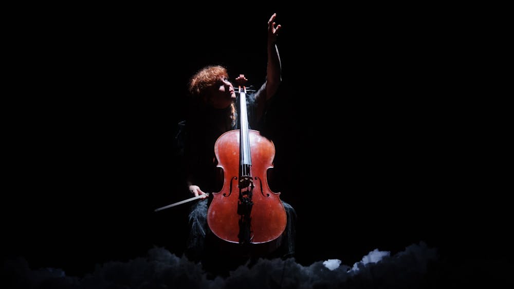 Zoë Barry playing cello and reaching up to the sky