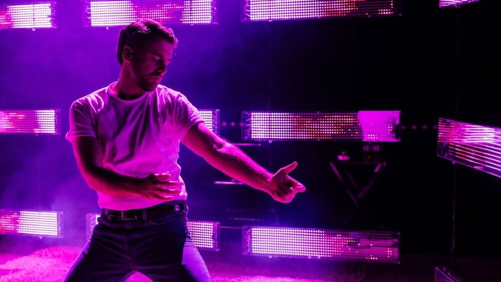 Simon Leary lit with pink and purple lighting as he waltzes with an invisible partner