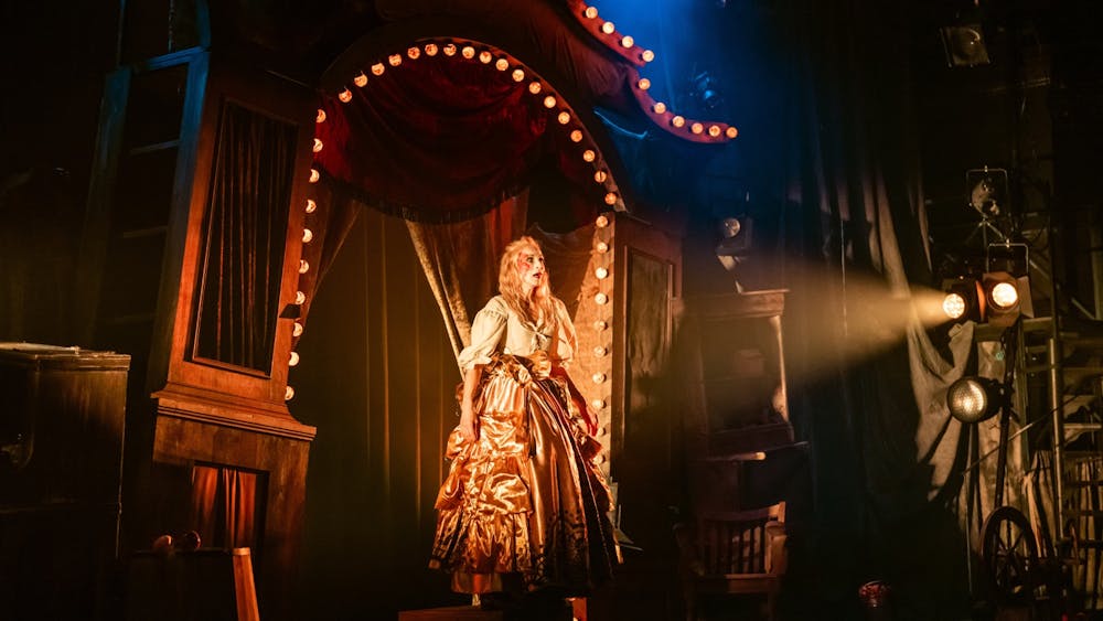 A woman standing in the lit-up arch of an old theatre
