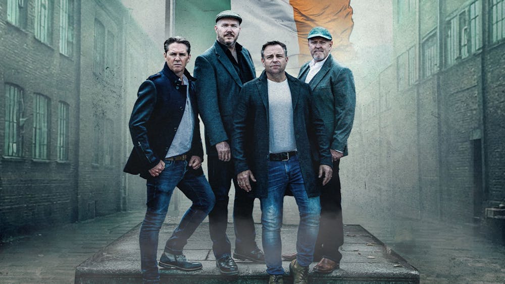 The four members of The High Kings standing in a brooding street with the Irish flag behind them