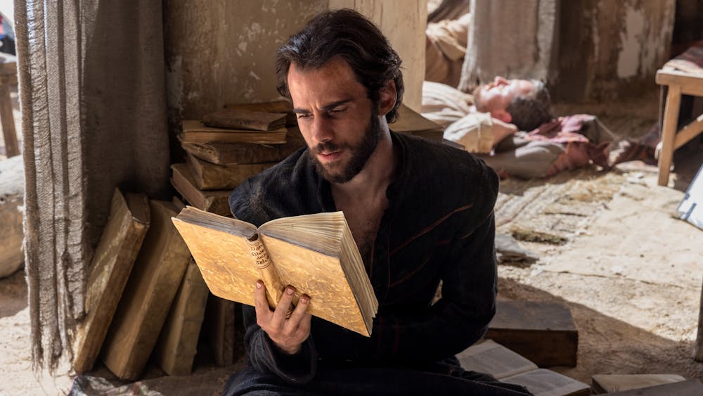 Man sits on ground reading book