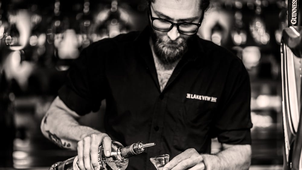 Bartender preparing a drink behind the bar at The Lake View Hotel.