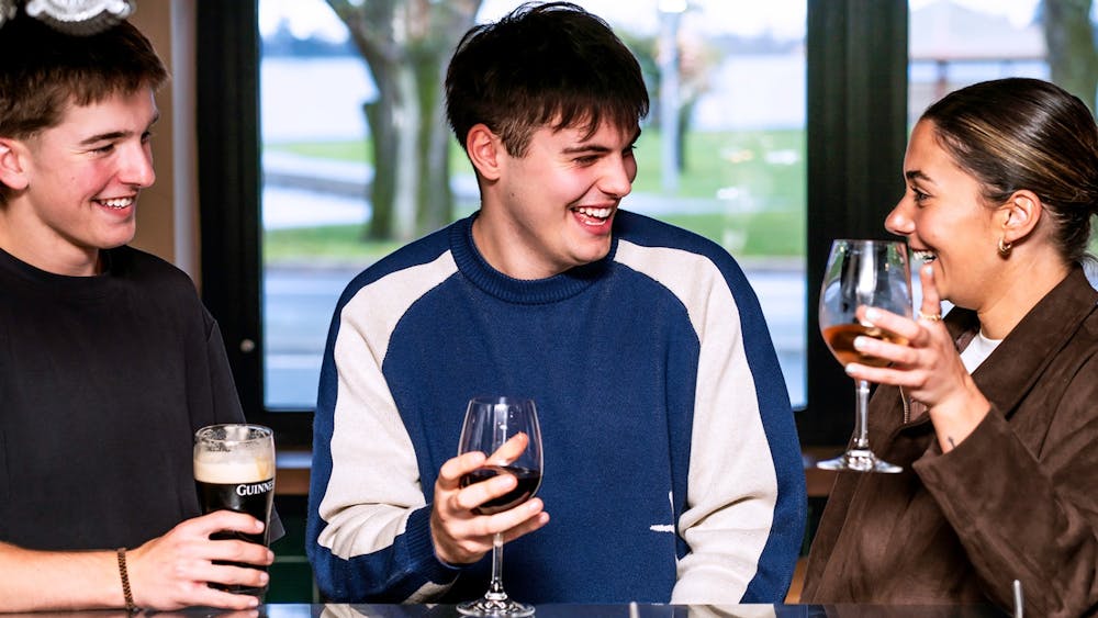 Three friends laughing together over drinks inside The Lake View Hotel.