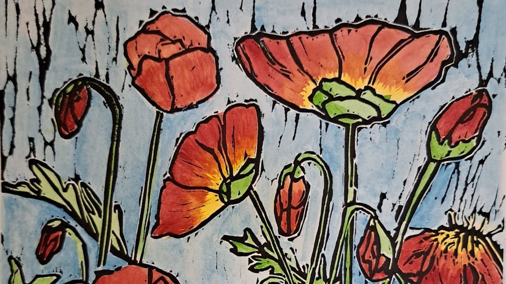 Lino print in black ink with colourful red poppies in a blue  background