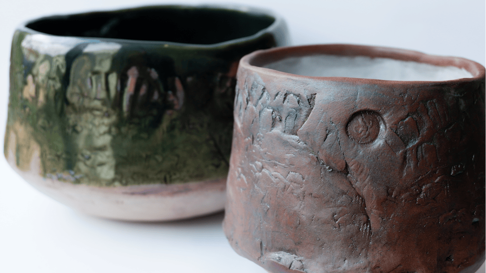 Two teabowls. One is green and the other brown