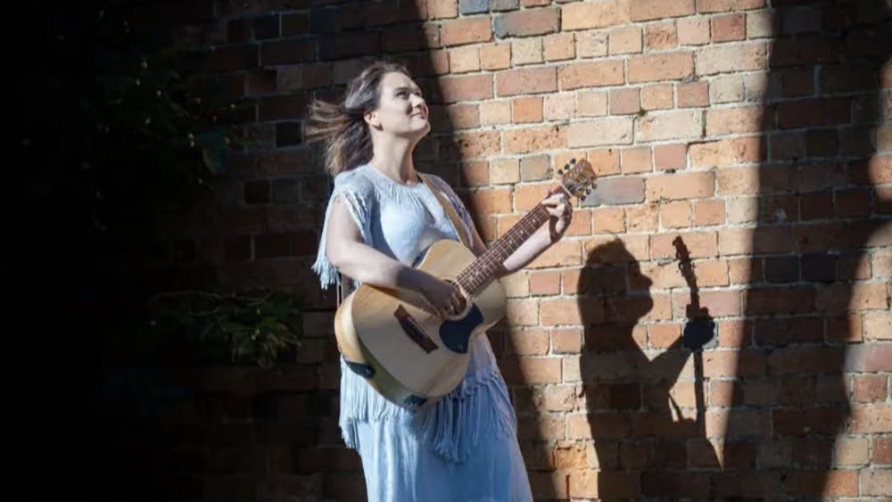 Woman in blue dress singing with guitar