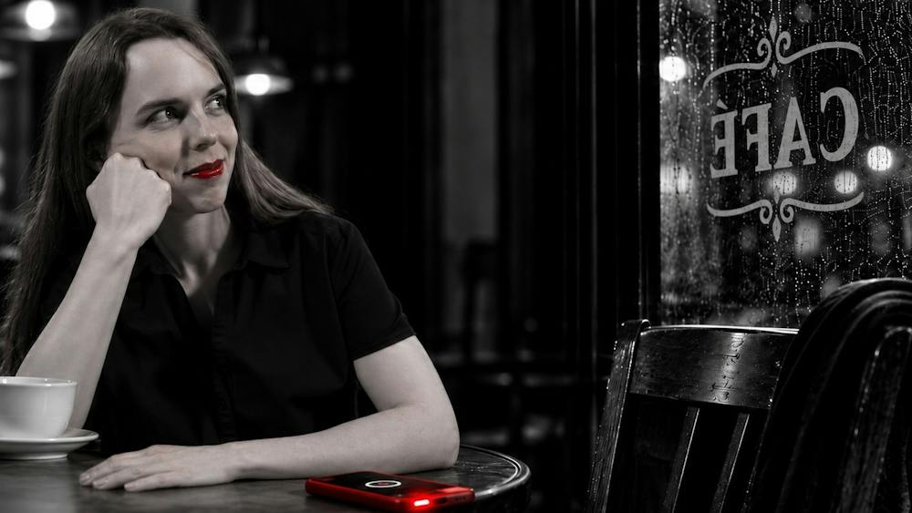 Jean sits at a café table beside a ringing red phone in Ballarat National Theatre’s Dead Man’s Cell