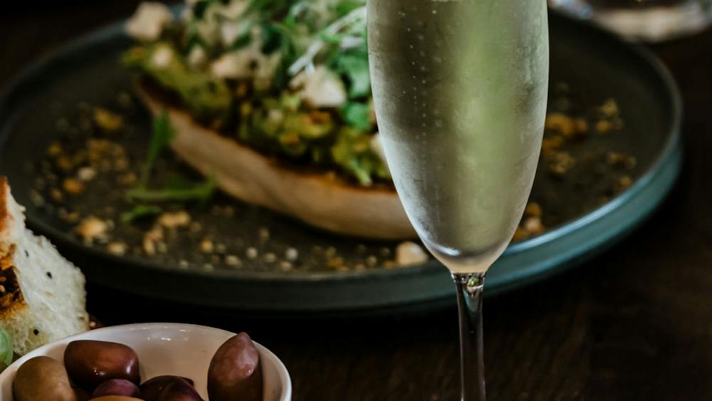 A glass of Champagne sits surrounded by plates of food