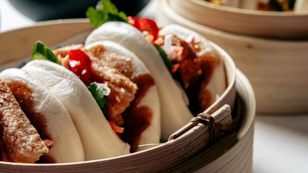 Close-up of three filled bao buns in a bamboo steamer.
