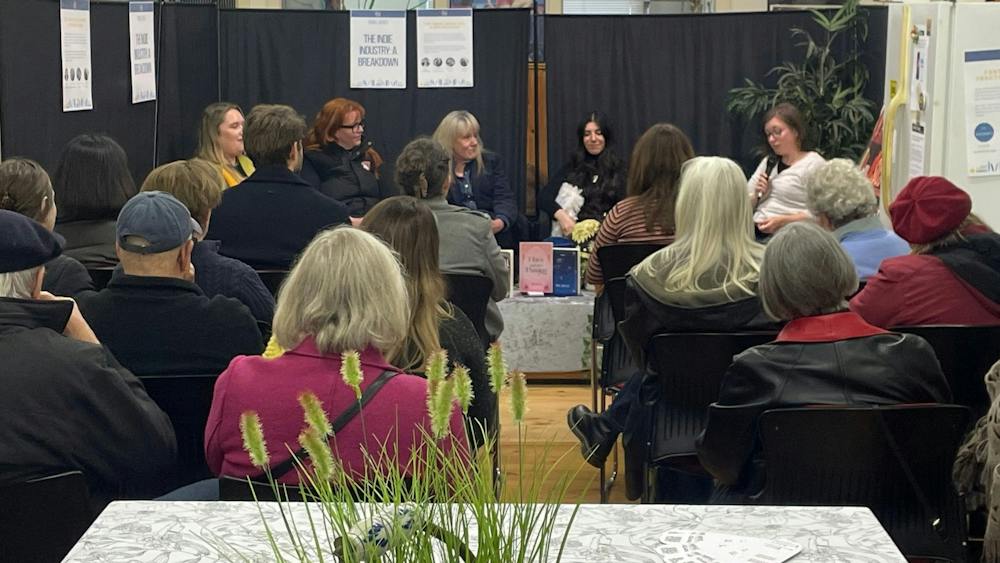Background features five women talking about publishing industry. Back of audience in foreground,