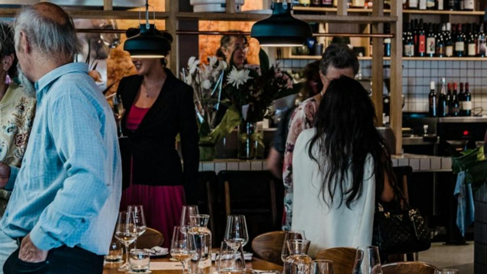 Guests inside the restaurant standing around the long table inside