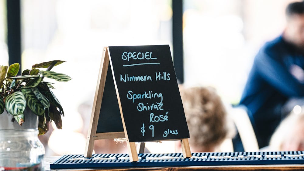 Image of bar with special sign, diners in the blurred background