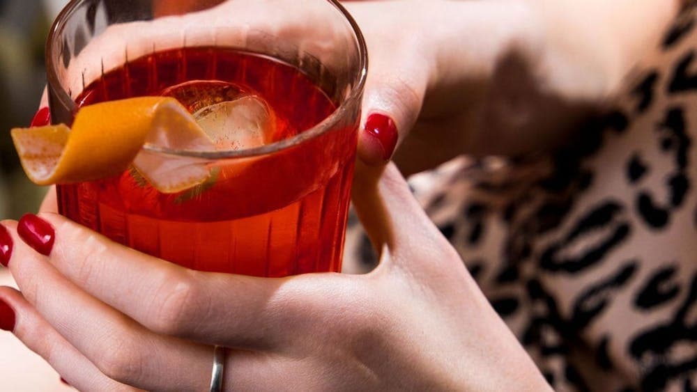 A cred cocktail in the hands of a lady with red fingernails