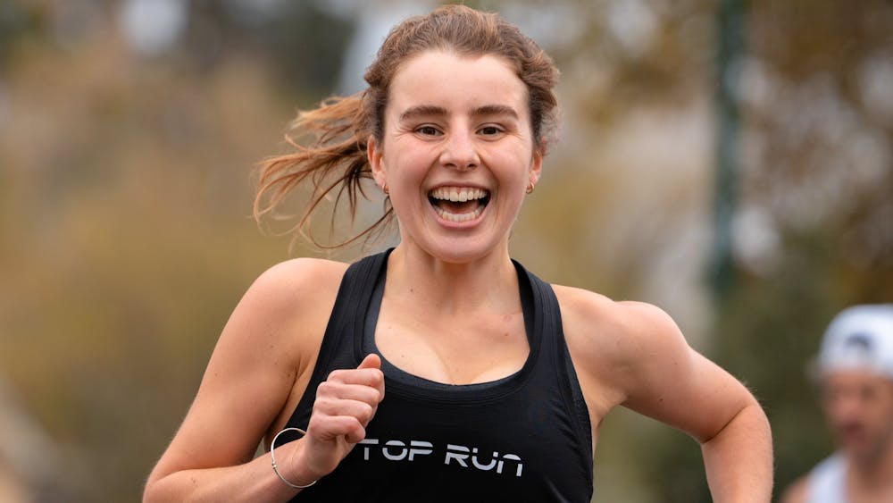 A female runner smiles at the camera as she jogs through Victoria Park, Ballarat