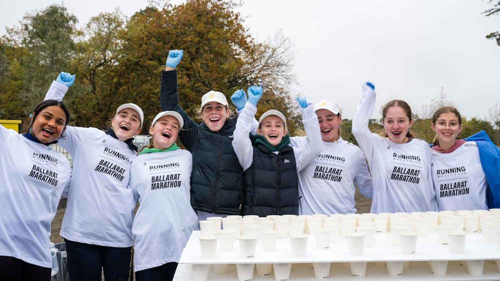 A group of volunteers in Victoria Park raise their hands and cheer at the 2025 Ballarat Marathon