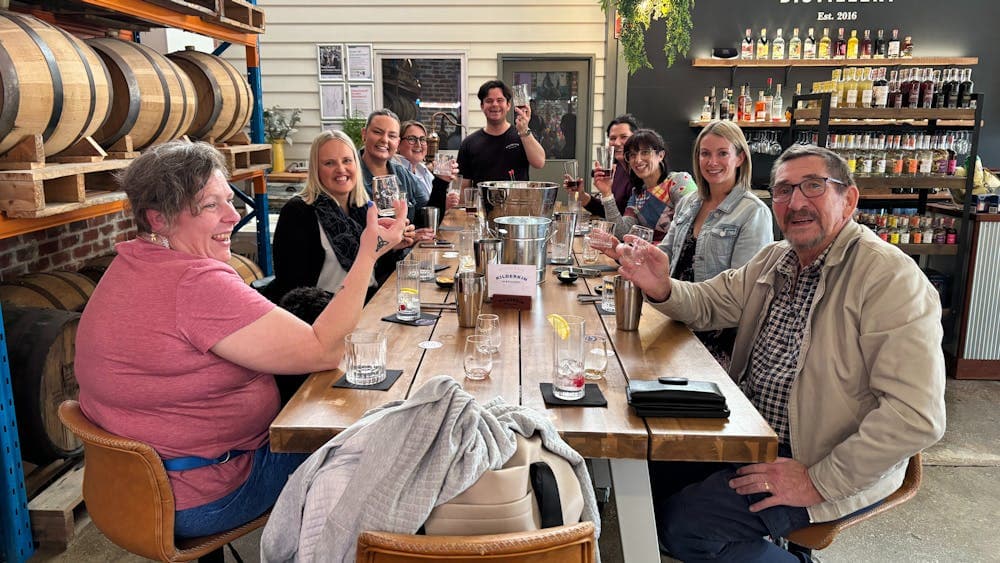 a group of people elarning to make cocktails and rasiing their glass in a toast
