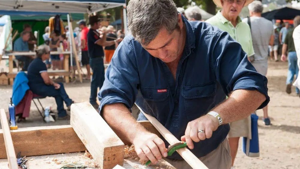 Man carving wood outside on bench