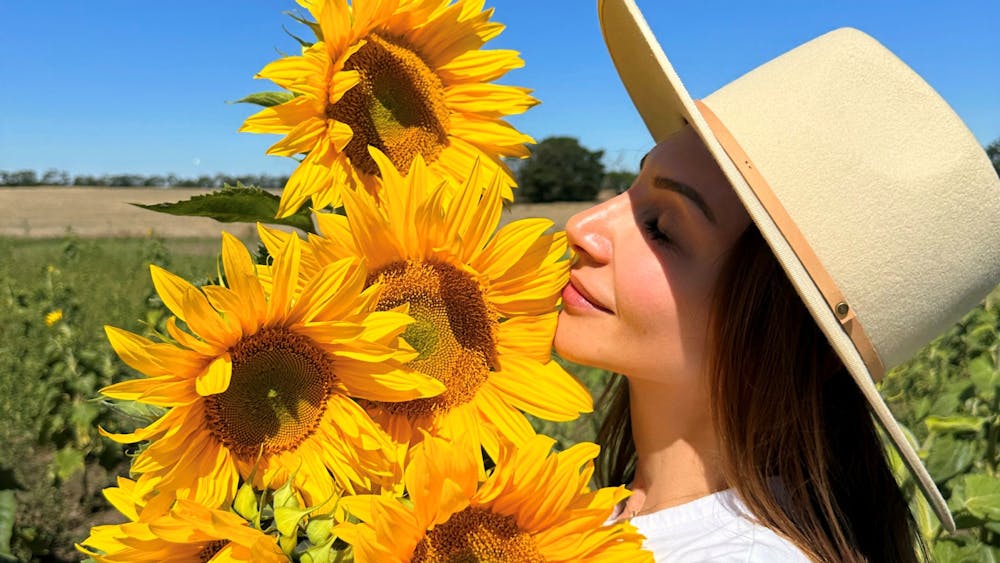 a lady in a hat admiring her sunflowers