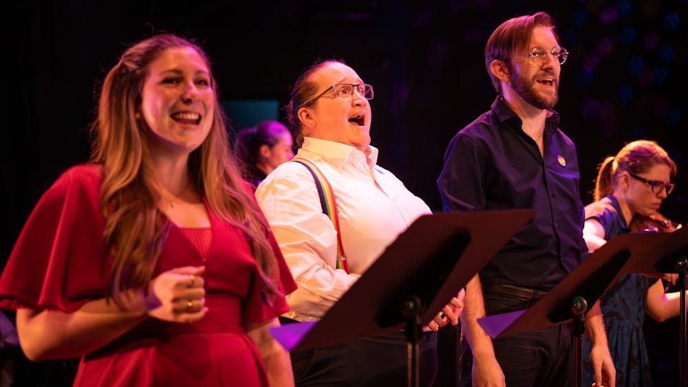 three singers smile while singing