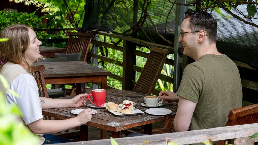 Couple sitting outdoors drinking coffee and eating scones