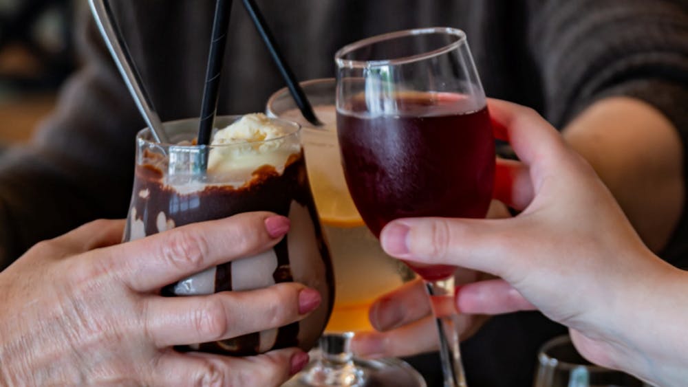 Guests clinking glasses over brunch with cocktails, coffee and sparkling wine.