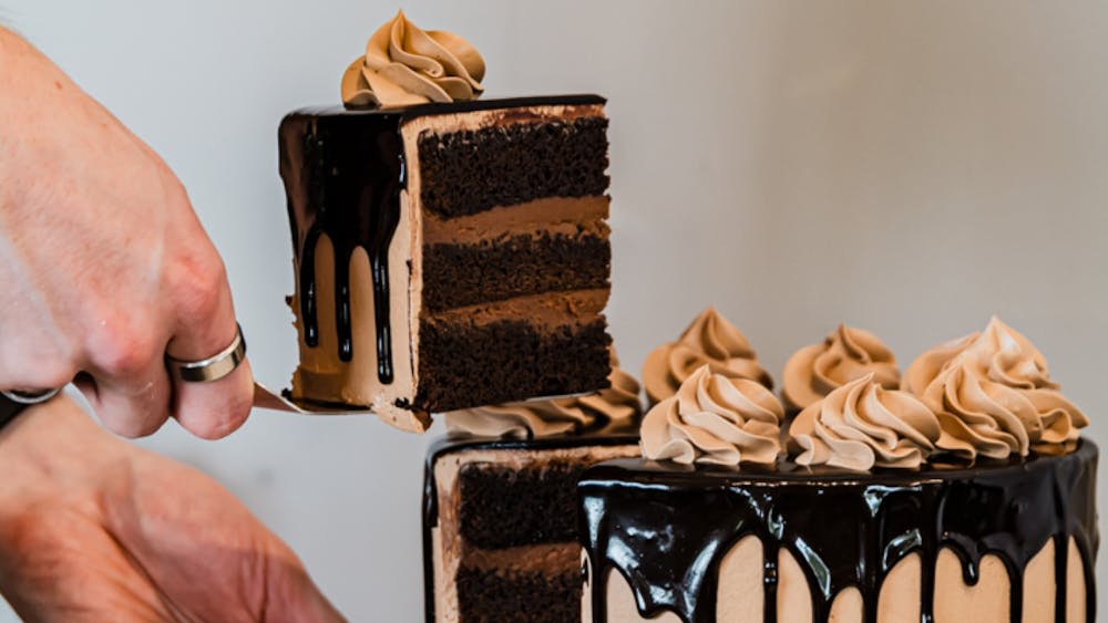 Slice of chocolate cake lifted from a layered cake with chocolate ganache