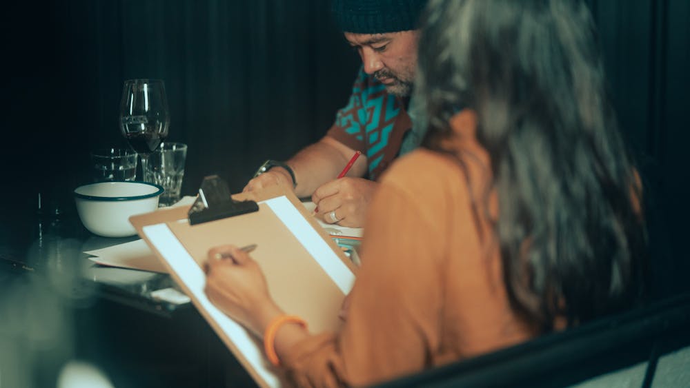 Two people drawing with wine on table
