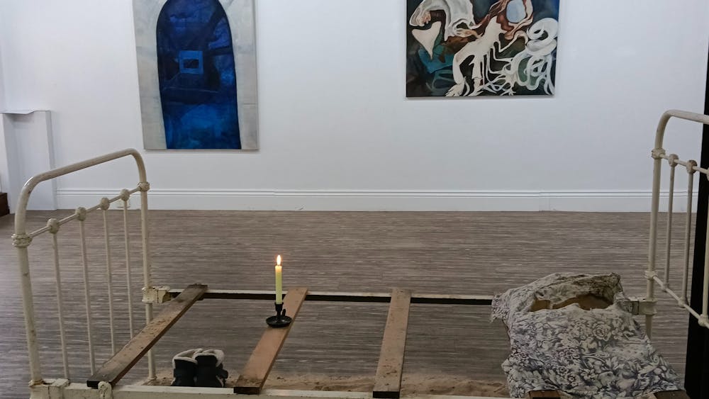 Forefront has a bed frame with sand placed beneath it and paintings on the wall.