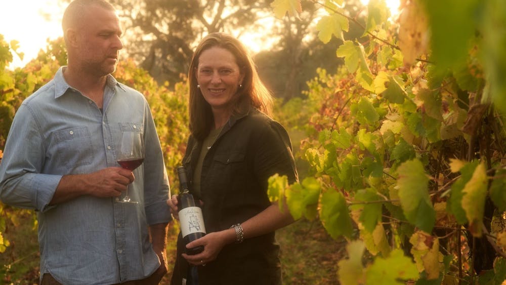 Adam & Nancy in vineyard with bottle of Nebbiolo