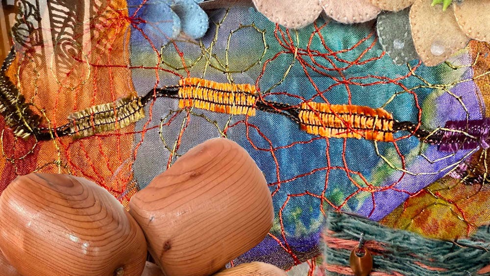 Colourful mixed-media craft display featuring hand-stitched textiles, felt flowers, woven fibres, wo