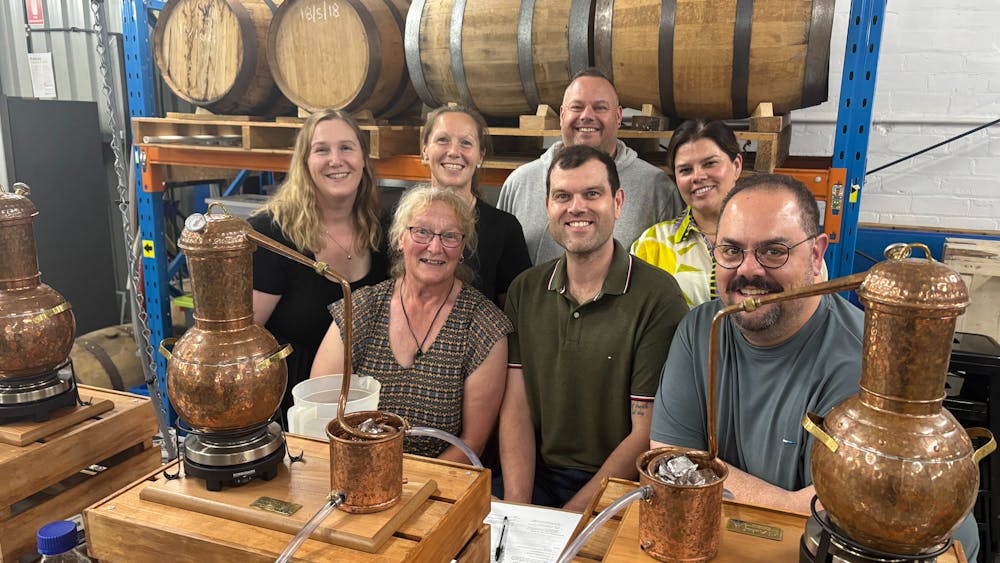 Seven adults in a group behind gin stills