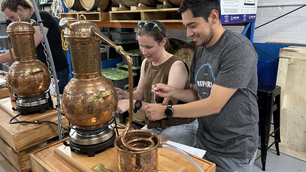 Two adults working with small still in bench