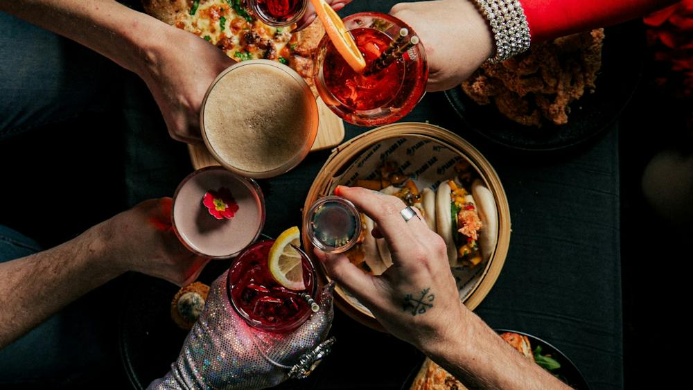 Overhead view of friends enjoying cocktails, bao buns, pizza and share plates at Piano Bar Ballarat.