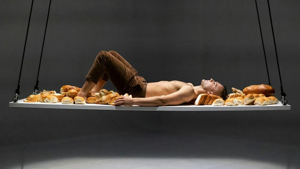 An acrobat lying on a suspended platform filled with bread
